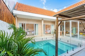 A modern house with a swimming pool, large windows, and a tiled roof. - Sacral Luxury Villa with a private pool (Canggu)