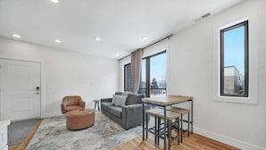 Uma sala de estar moderna com sofá, apoio para os pés e mesa de jantar.