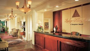 A reception area with a wooden reception desk, a chandelier, and a wall with the name 'Lodge Alley Inn' and 'Bluegreen Resort' written on it. - Bluegreen's Lodge Alley Inn: Historic Charm, Modern Comfort, Top Location-Studio (Charleston)
