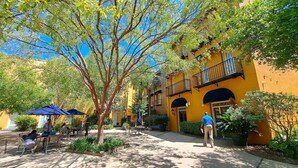 A courtyard with outdoor seating, a tree, and a yellow building with balconies. - Bluegreen's Lodge Alley Inn: Historic Charm, Modern Comfort, Top Location-Studio (Charleston)
