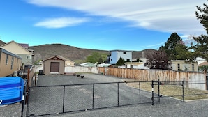 Un barrio residencial con casas, un patio cercado y montañas al fondo.