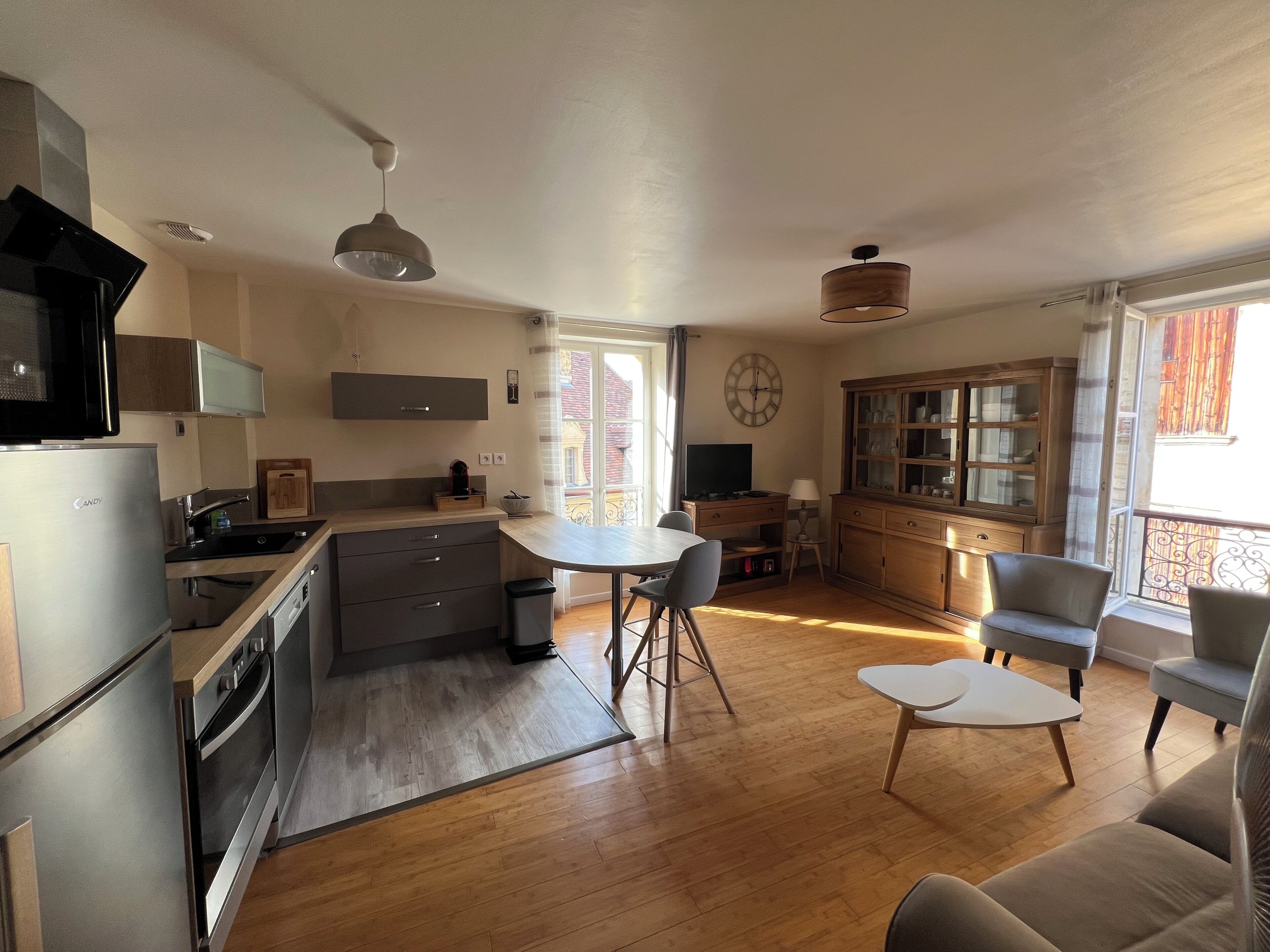 Une cuisine moderne équipée d’un four à micro-ondes, d’un réfrigérateur et d’une cuisinière. On y trouve également un coin repas avec une table et des chaises, ainsi qu’un salon avec un canapé et une table basse.