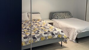 Une chambre avec deux lits, une lampe sur pied et une petite table.