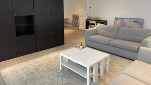 Un salon moderne avec un canapé gris, une table basse blanche et un meuble de rangement noir.