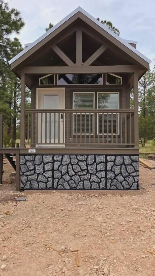 A cabin with a stone base, a balcony with railings, and a pitched roof. - Luxury Cabin with Forest View 7B (Williams)