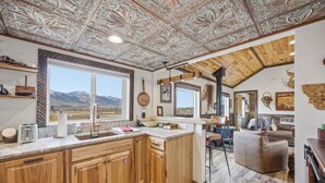 Un interior rústico con una cocina de madera, un ventanal y vistas a las montañas.