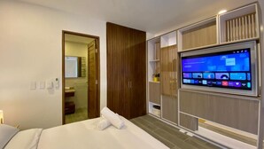 A modern hotel room with a bed, a TV, a wardrobe, and a bathroom visible through an open door. - Casa Sisiguaca by Xarm Apartments (Santa Marta)