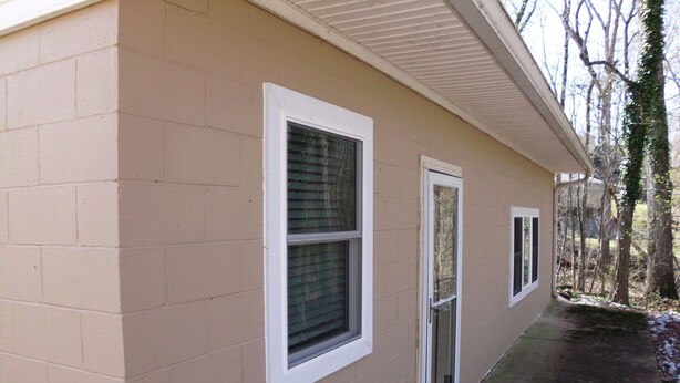 A building with beige exterior walls, two windows with white frames, and a concrete pathway leading to the entrance. - Fantastic 2-bedrm cabin with AC on Kentucky Lake, near Paris Landing State Park. (Springville)