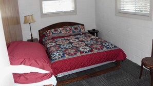 A bedroom with a bed, a nightstand, a lamp, a chair, and two windows. - Fantastic 2-bedrm cabin with AC on Kentucky Lake, near Paris Landing State Park. (Springville)