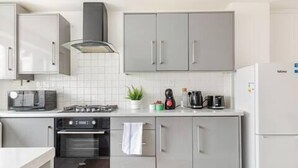 Una cocina moderna con armarios grises, microondas, estufa, horno y cafetera.