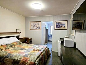 Ein Hotelzimmer mit Bett, Schreibtisch, Stuhl und Mikrowelle.