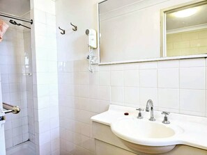 Ein Badezimmer mit Waschbecken, Spiegel und Duschbereich.