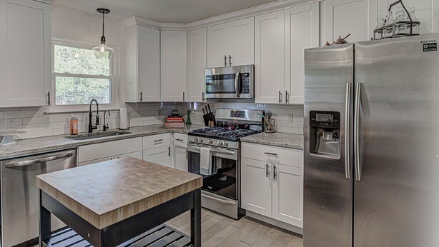 A modern kitchen with white cabinets, stainless steel appliances, and a central island. - Awake to Adventure, then Recharge and Relax in Historic Georgetown, Texas! (Georgetown)