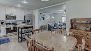 A modern kitchen with white cabinetry, a dining area with a wooden table and chairs, and a living room with a sofa and coffee table. - Awake to Adventure, then Recharge and Relax in Historic Georgetown, Texas! (Georgetown)