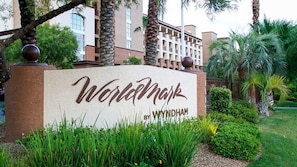 Un cartel con la leyenda 'Worldmark by Wyndham', rodeado de follaje y palmeras.