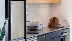 Een moderne keuken met roestvrijstalen apparatuur, houten kastjes en een betegelde spatwand.