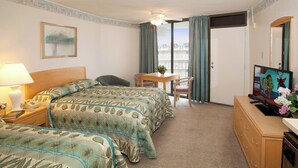 Une chambre d’hôtel avec deux lits, un bureau, une chaise, une télévision et une fenêtre avec des rideaux.