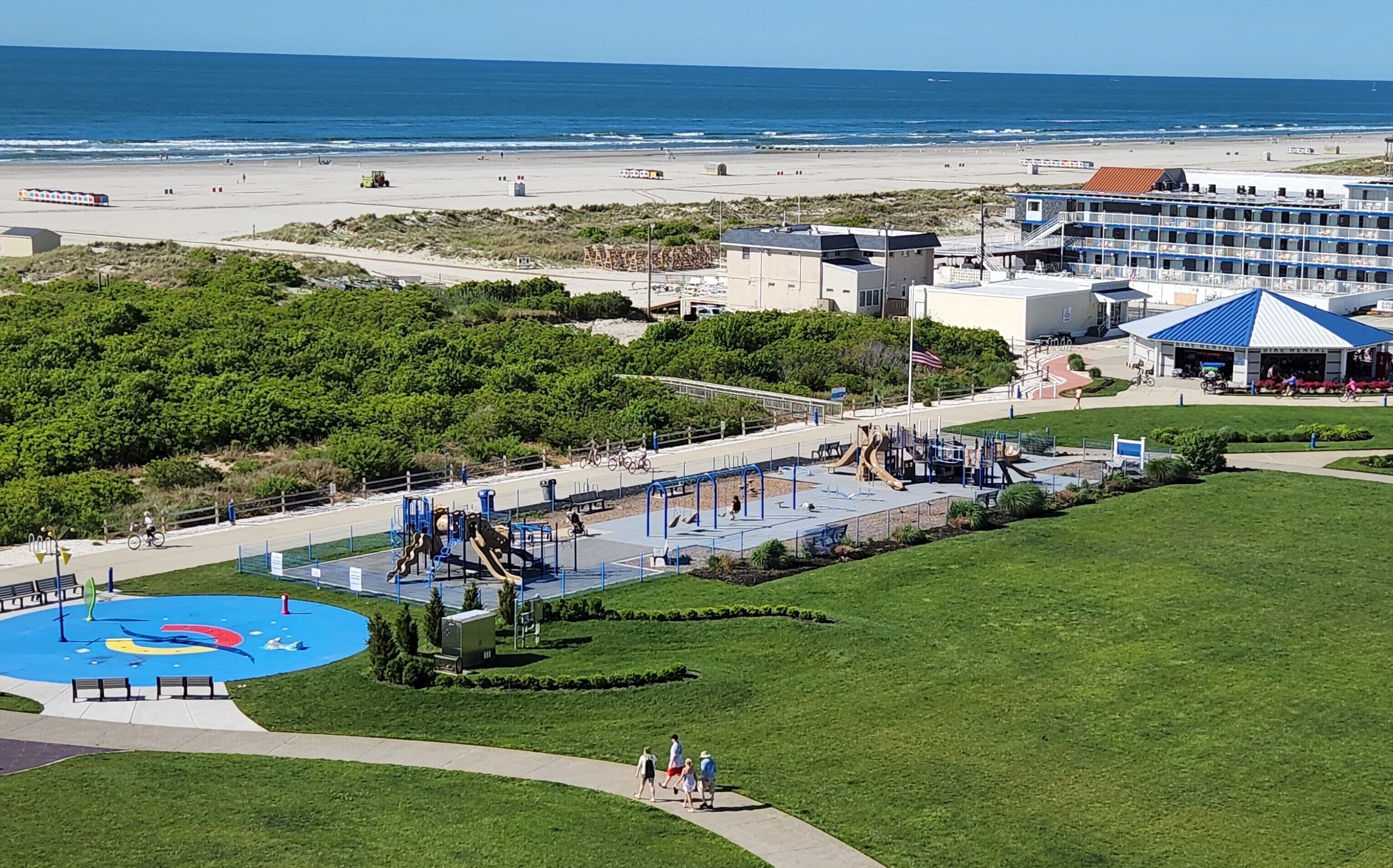 A beachside hotel with a playground, a pool, and a view of the ocean.
