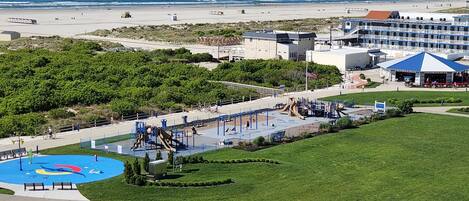 A beachside hotel with a playground, a pool, and a view of the ocean.