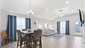 Amplia sala de estar con una mesa de comedor, sillas, un sofá y un ventilador de techo.