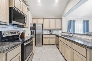 Eine moderne Küche mit Granit-Arbeitsplatten, Edelstahlgeräten und hellen Holzschränken.