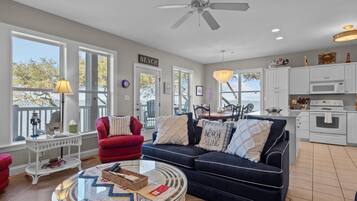 A spacious living area with a large window, a ceiling fan, and a dining area with a view.