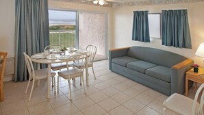 Un comedor con una mesa dispuesta para cuatro, un sofá y una ventana con cortinas.