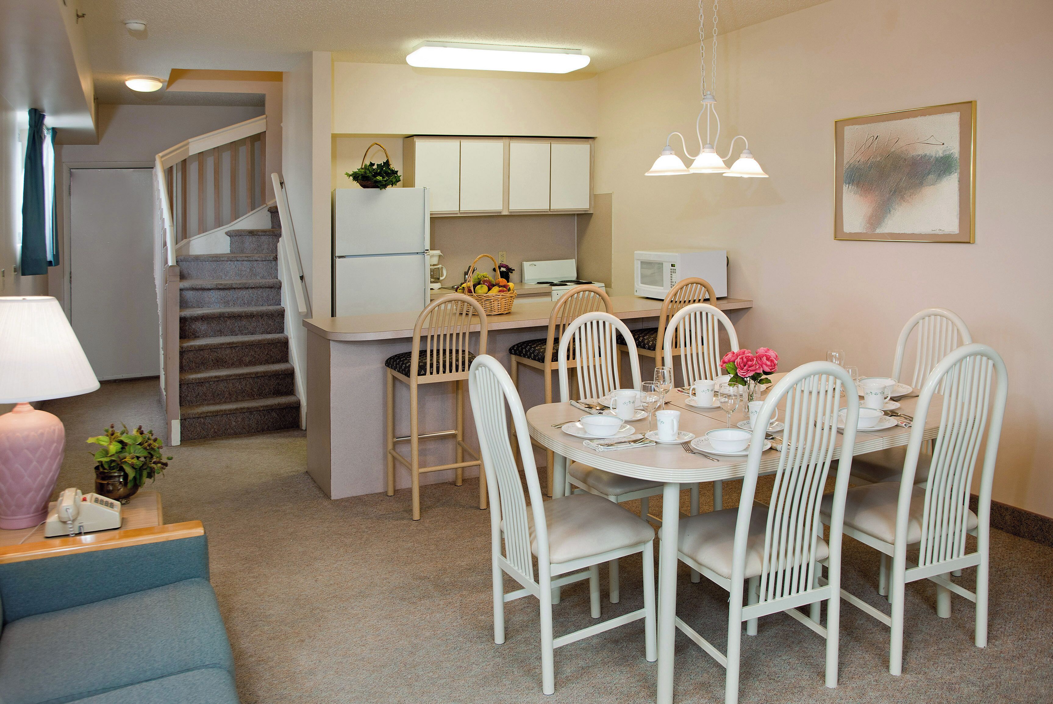 A compact kitchen with a dining area, a staircase, and a small living space.