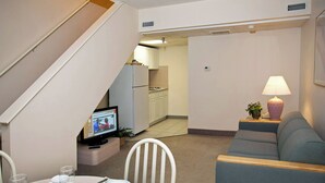 A dining area with a table set for two, a television, and a sofa. - Lotus Inn - Overview Townhouse - 2 Bedroom (Wildwood Crest)