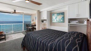 Een kamer met een bed, een eettafel en uitzicht op zee.