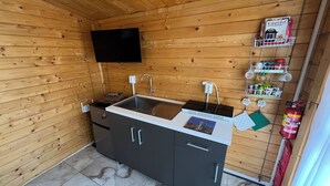 A compact kitchen with a built-in stove, sink, and a flat-screen TV mounted on the wall. - Cozy 1-bedroom cabin perfect for 2 in Willemstad (Willemstad)