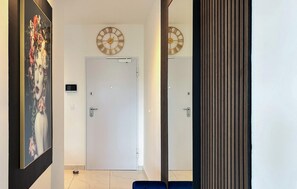 A hallway with a white door, a wall-mounted clock, a security camera, and a blue bench. - 2 bedroom awesome apartment in Turanj (Turanj)