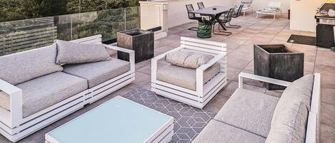 A rooftop patio with a sofa, a table, and a dining area.