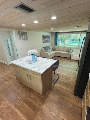 A modern kitchen with a marble island, wooden cabinets, and a built-in refrigerator. - Weeki Wachee Main River • Kayaks • Private Stairs • Large Yard • Manatees (Spring Hill)
