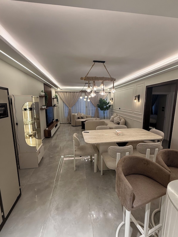 A modern kitchen with a dining area, a refrigerator, and a television.
