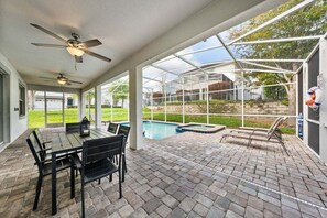 Un patio couvert avec une piscine, des sièges d’extérieur et des ventilateurs de plafond.