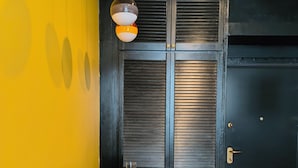 Una habitación con una puerta negra, una pared amarilla y una mesa dispuesta con platos y vasos.