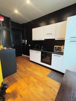 Une cuisine moderne avec des meubles blancs, un four à micro-ondes et une cuisinière.