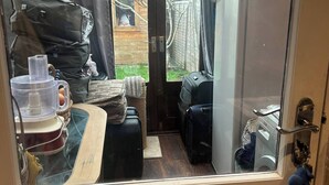 Cozinha compacta com geladeira, uma mesa pequena e janela com vista para um quintal.