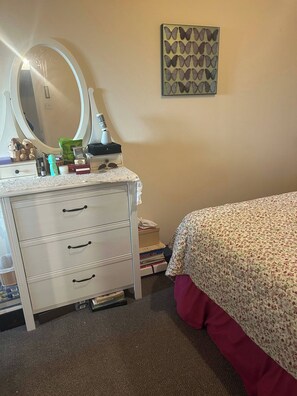 A bedroom with a bed, a dresser with drawers, a mirror, and a wall decoration. - Cosy Family Home With Full Amenities (Uxbridge)