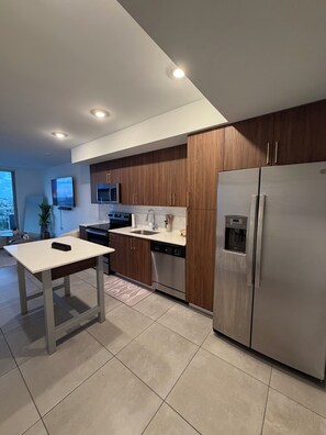 Een moderne keuken met houten kastjes, roestvrijstalen apparatuur en een eethoek met een tafel en stoelen.