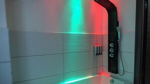 Une salle de bain moderne équipée d’une douche, d’un panneau de commande et d’un éclairage à LED.