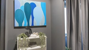 Une pièce avec un grand tableau abstrait, une machine à café et une petite plante posée sur une étagère.