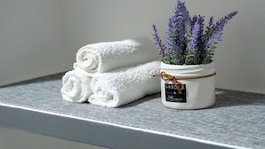 Une serviette blanche, un pot blanc avec une étiquette et une plante posée sur une surface texturée.