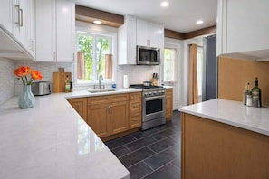A modern kitchen with white cabinets, a stainless steel stove, and a microwave.