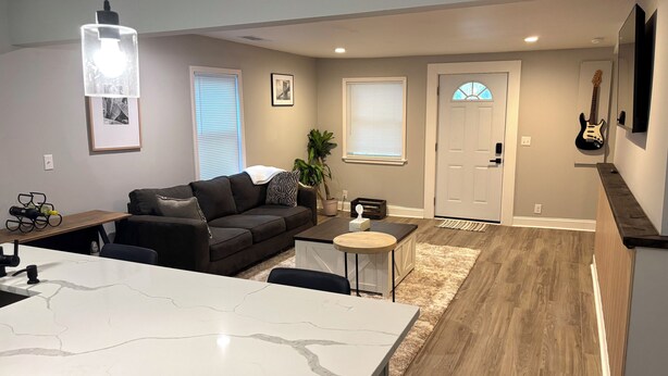 A modern living room with a sofa, a coffee table, and a kitchen area with a marble countertop.