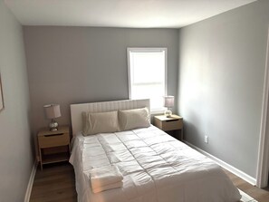 A bedroom with a bed, two bedside tables, a window, and a door. - Walk to downtown Athens, relax in this stylish 2BR/2BA home near everything UGA (Athens)
