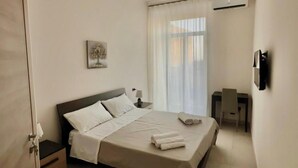 A modern bedroom with a single bed, bedside tables, a desk, and a chair. - B&b SunHouse (Napoli)