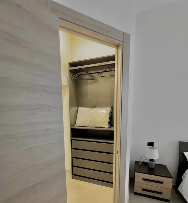 A walk-in closet with hanging space, shelves, and drawers. - B&b SunHouse (Napoli)