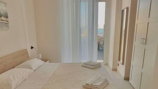 A hotel room with a bed, a window with curtains, an air conditioning unit, and a wardrobe. - B&b SunHouse (Napoli)